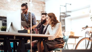 Immagine di tre persone che si confrontano davanti a un computer